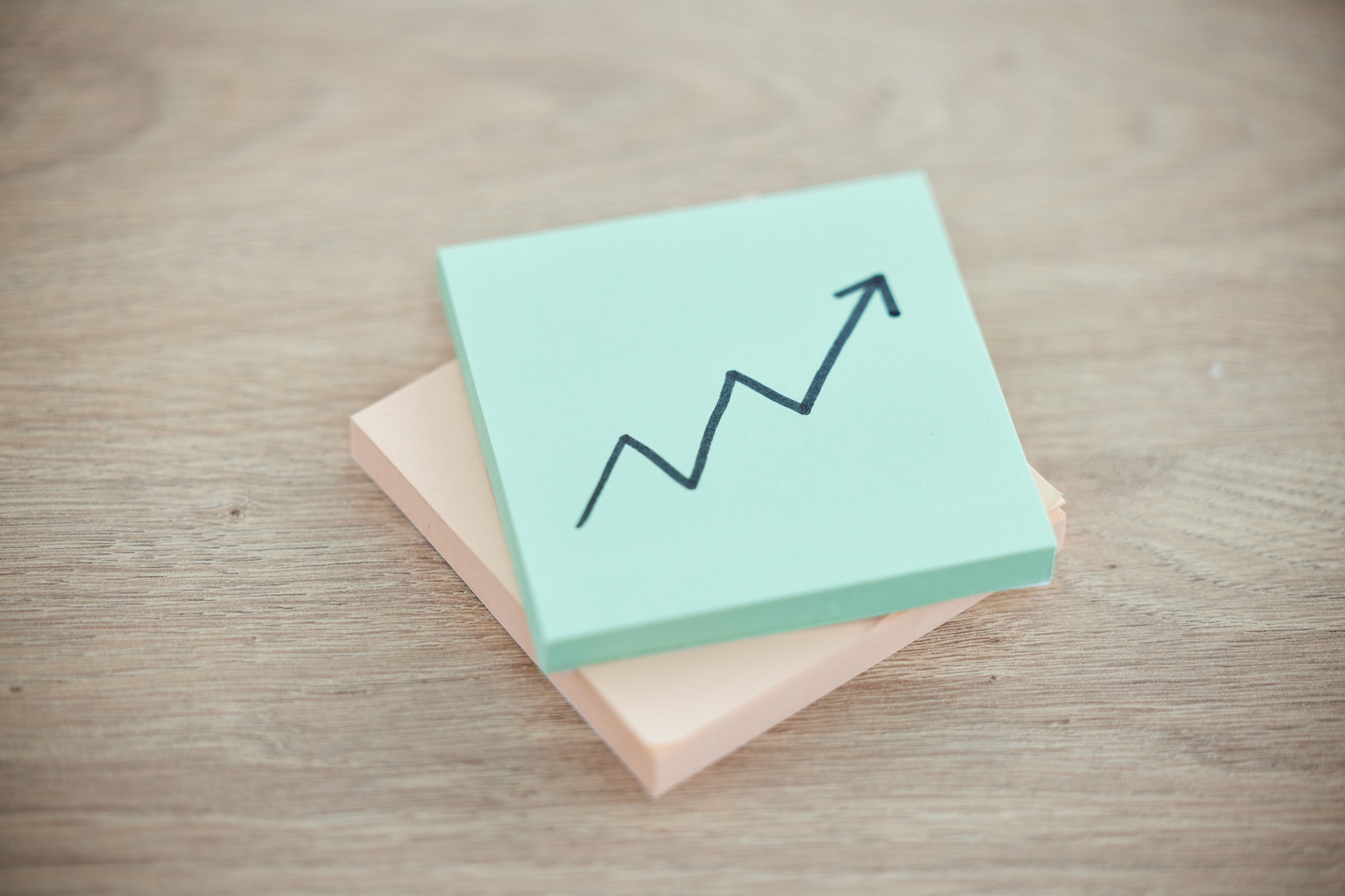 Growth, investment and success with arrow on sticky note for finance, stocks and goal. Price increa