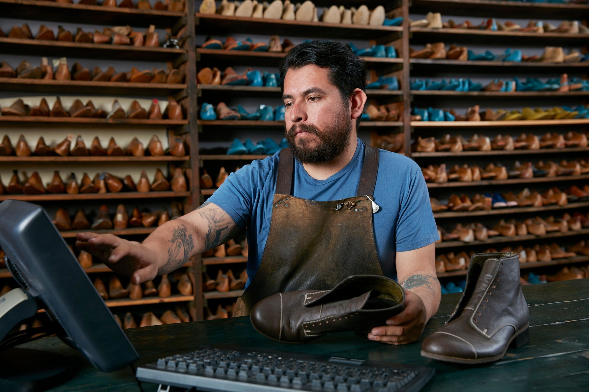 Male cobbler making invoice for boots in traditional shoe shop