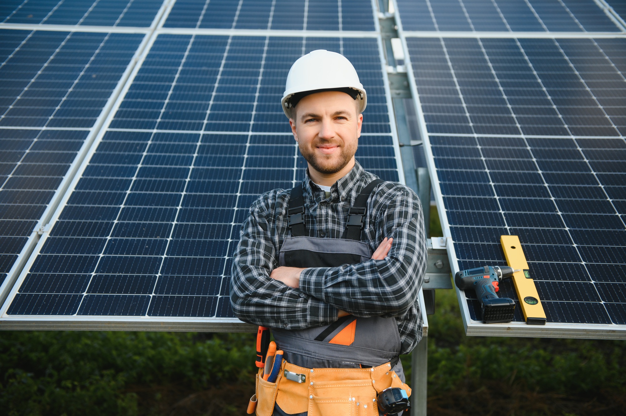 A handyman standing on the rooftop with solar panels and smiling at the camera.