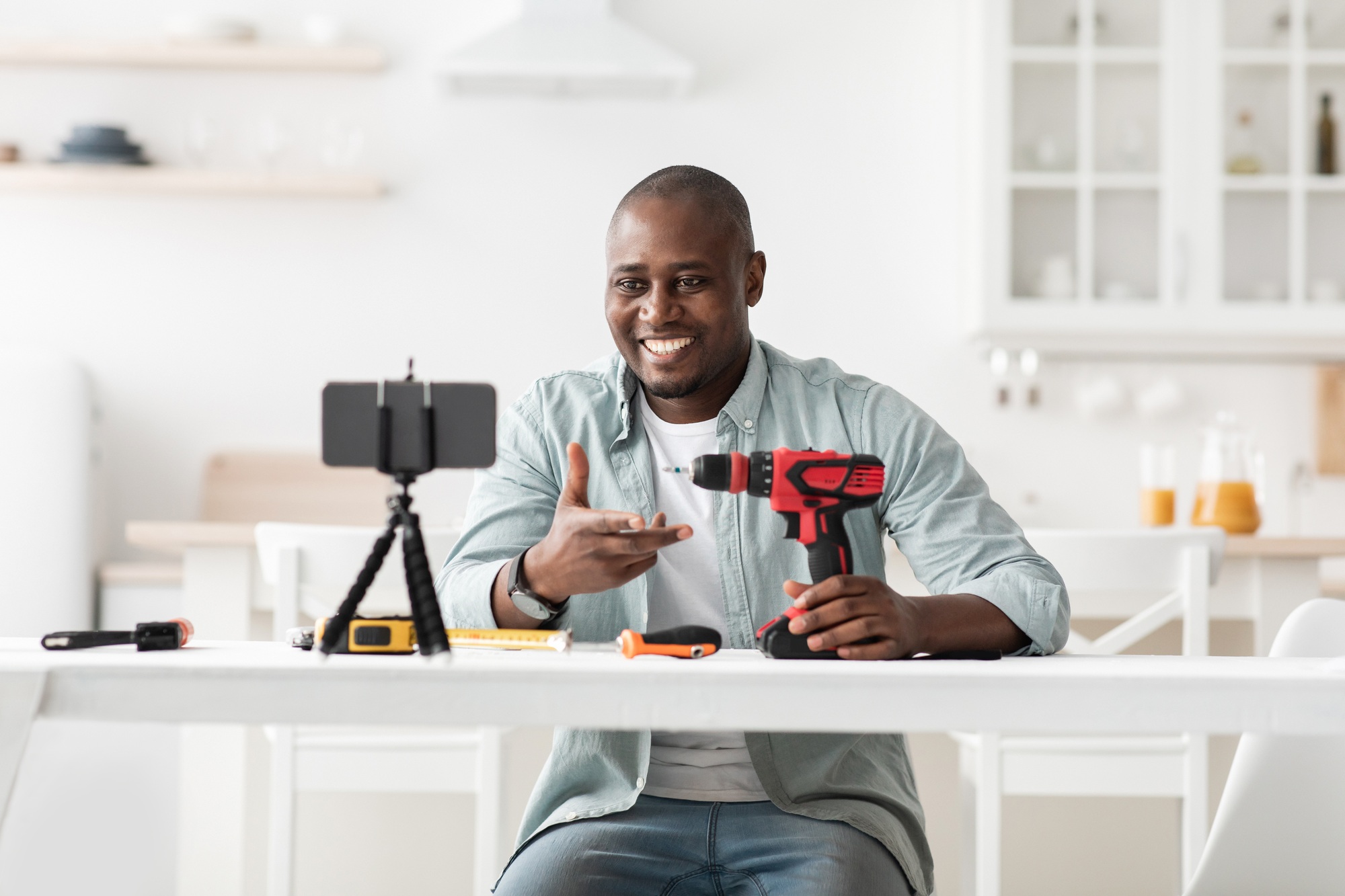 African american handyman recording video review of instruments, showing electric screwdriver and