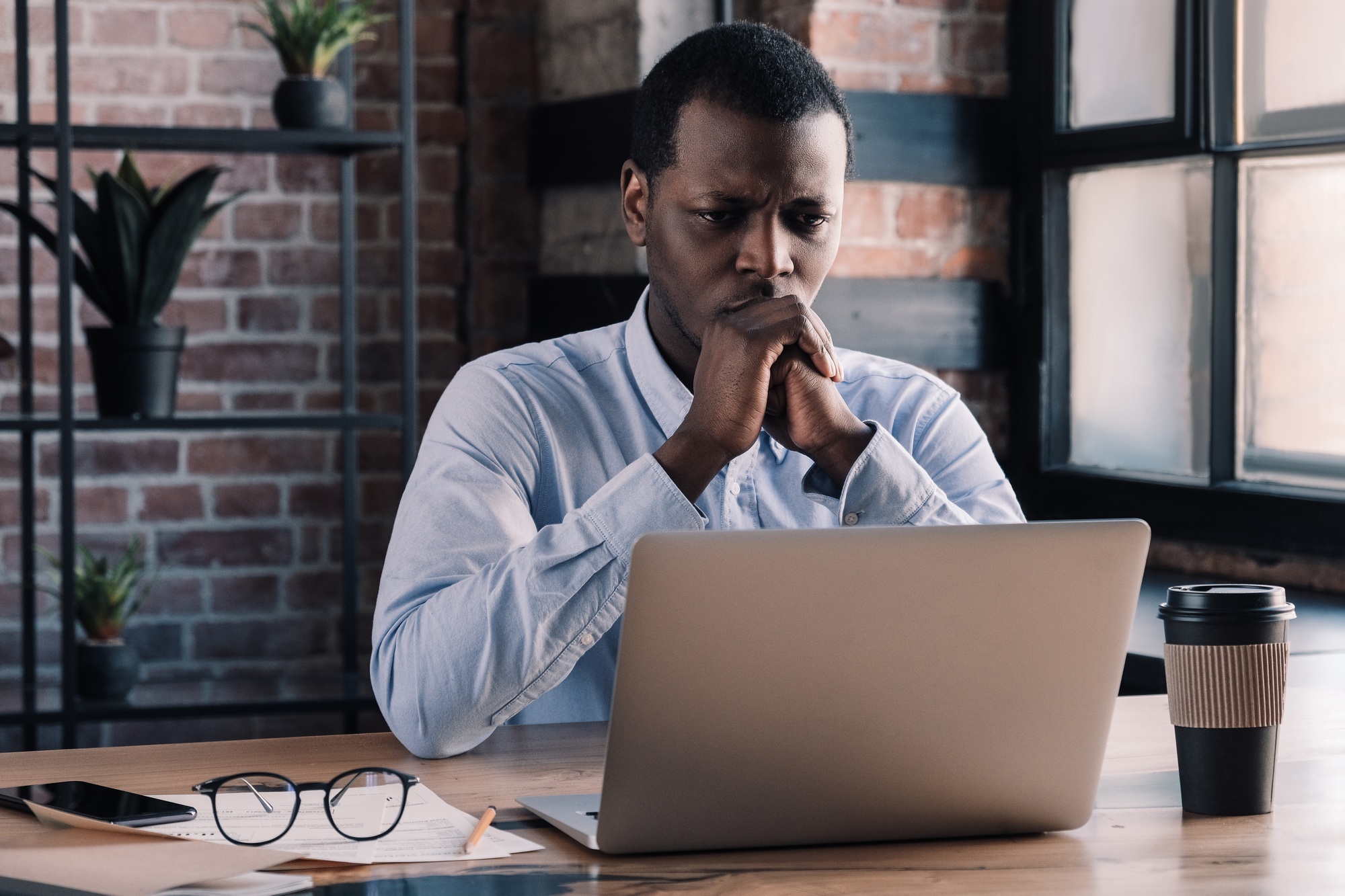 Casual african american man works on project at office thinking of financial risks