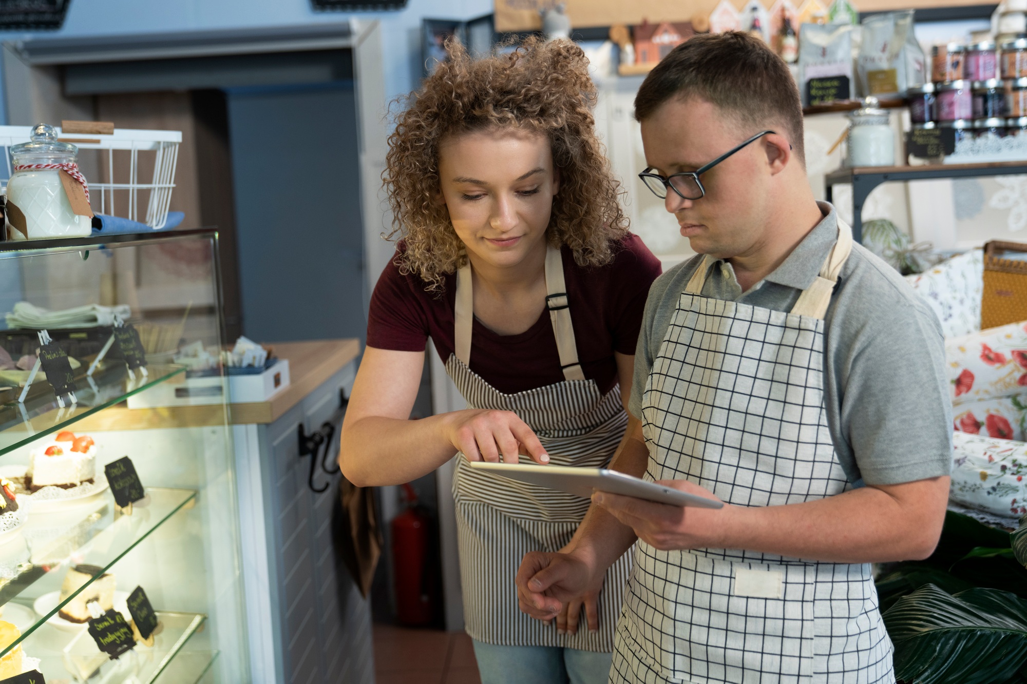 Caucasian man with down syndrome doing fridge inventory in a cafe using digital tablet
