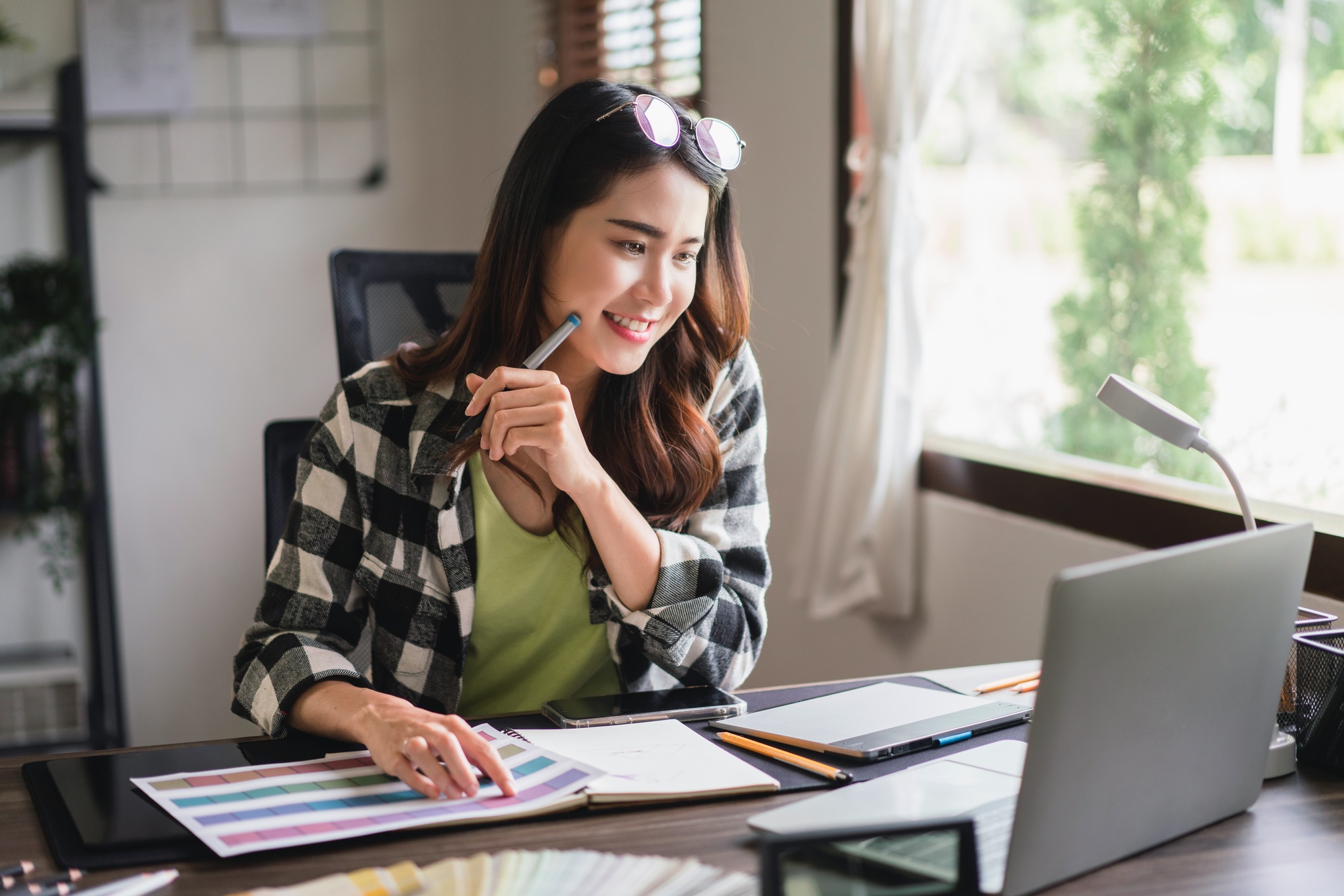 Female artist designer working on laptop to thinking design idea and drawing logo on graphic tablet