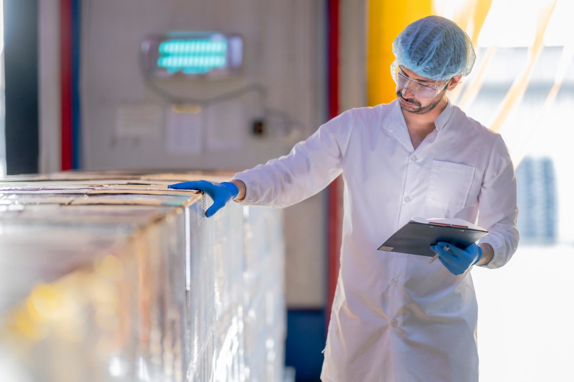 professional in a white lab coat and protective gear inspects inventory
