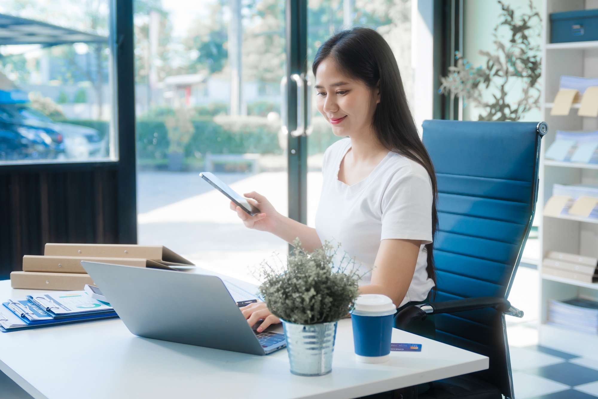 Young Asian woman at desk, analyzing credit reports, financial charts, and assessing credit risks.