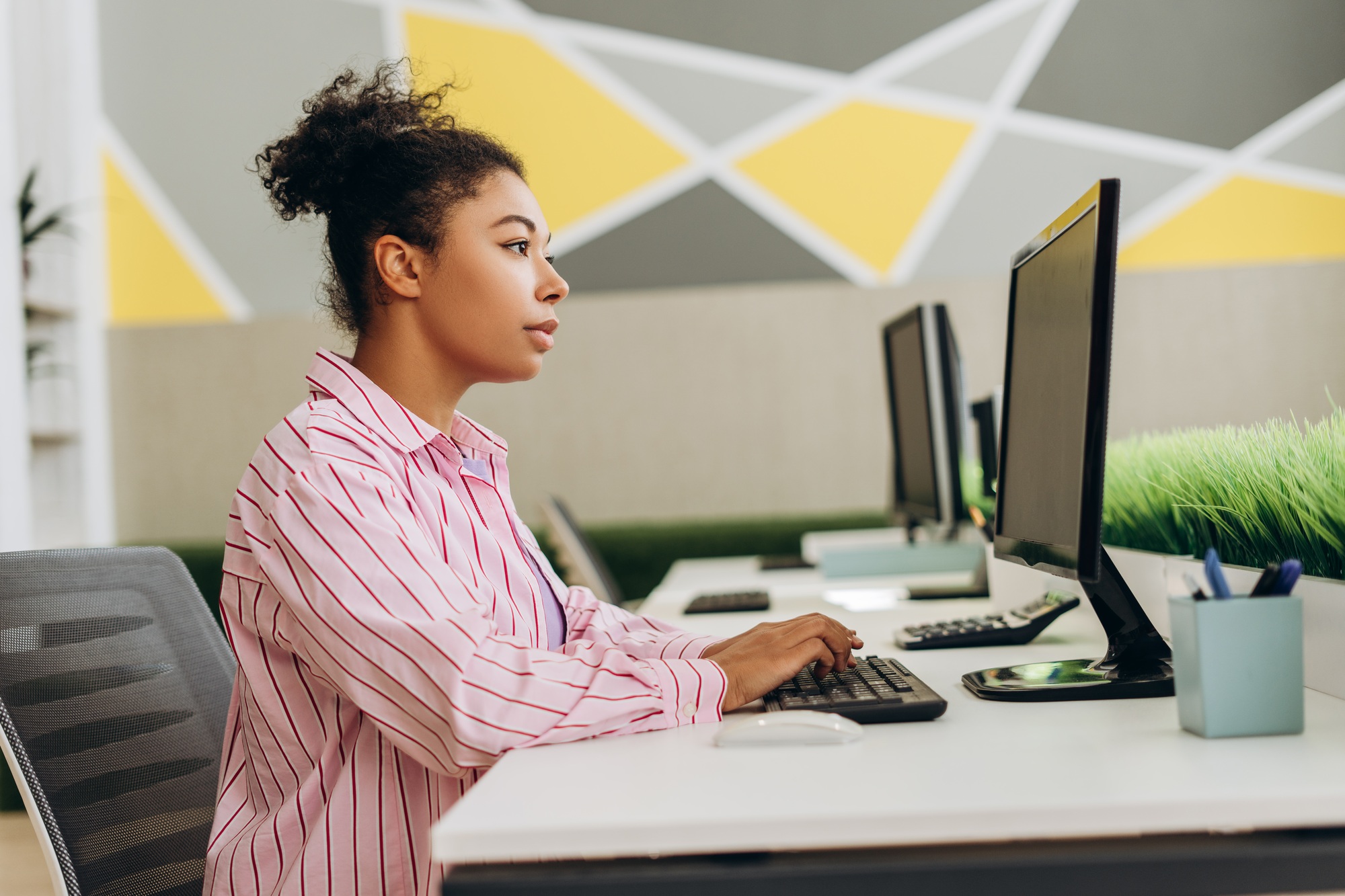 Focused employee typing on keyboard in modern office