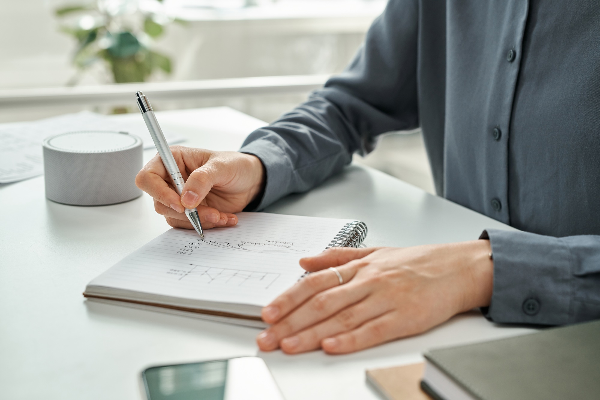 Manager writing financial strategy in notepad