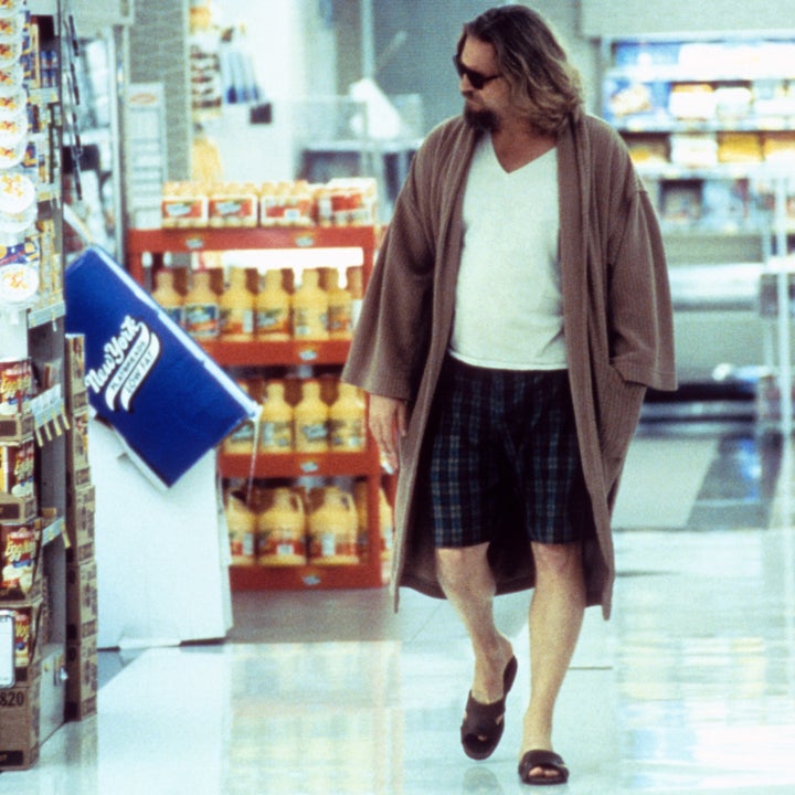 Person in a robe, T-shirt, and shorts, wearing sunglasses, walking through a grocery store aisle