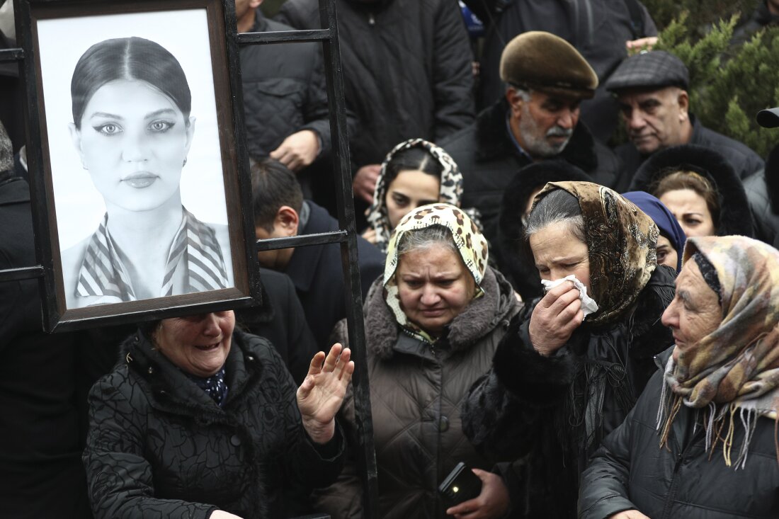 People mourn at the grave of flight attendant Hokume Aliyeva during a funeral of the crew members of the Azerbaijan Airlines Embraer 190 killed in a deadly plane crash in Kazakhstan this week, at the II Alley of Honor in Baku, Azerbaijan, Sunday, Dec. 29, 2024.