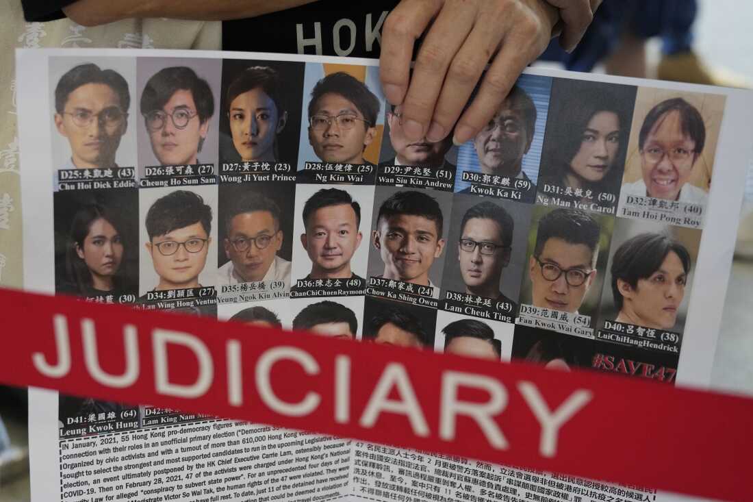 A supporter holds a placard with the photos of some of the 47 pro-democracy defendants outside a court in Hong Kong, on July 8, 2021.