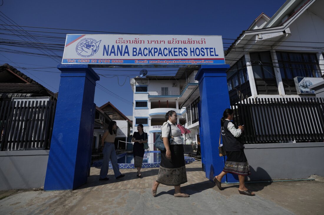 Health officials come out of Nana Backpackers Hostel after checking documents in Vang Vieng, Laos, on Friday.