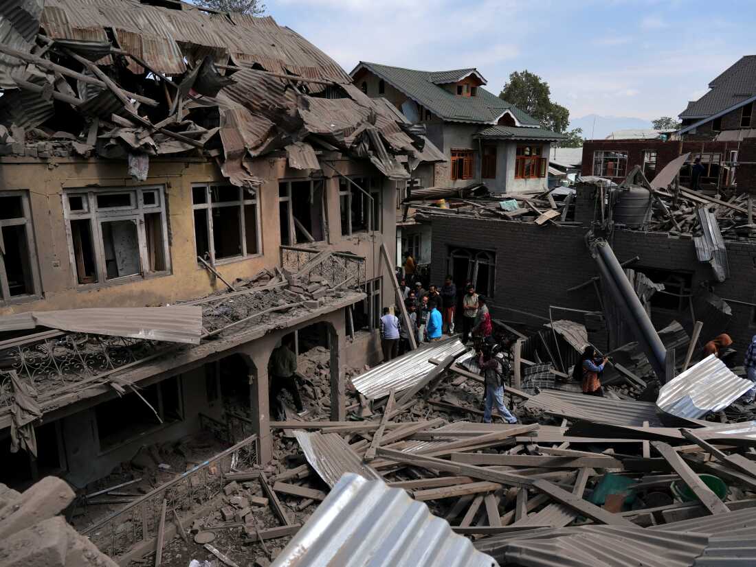 People stand near the razed house of alleged Kashmiri militant Ahsan Ul Haq Sheikh's family house in Murran area of Pulwama district on April 26, 2025