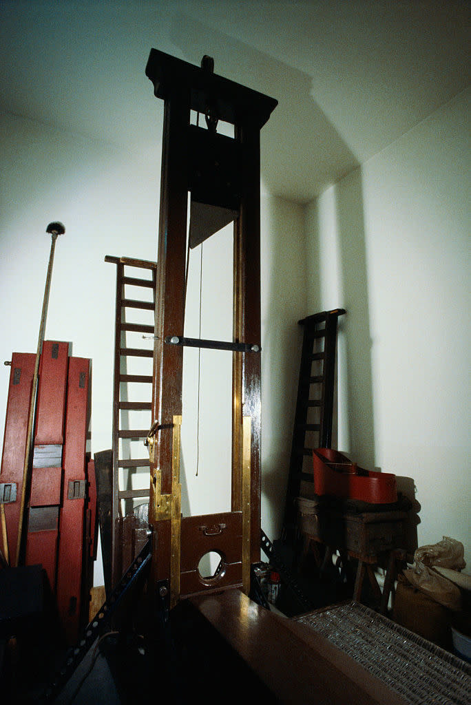A vintage guillotine, standing in a room with tools and equipment, highlighted for historical context in a rewind article