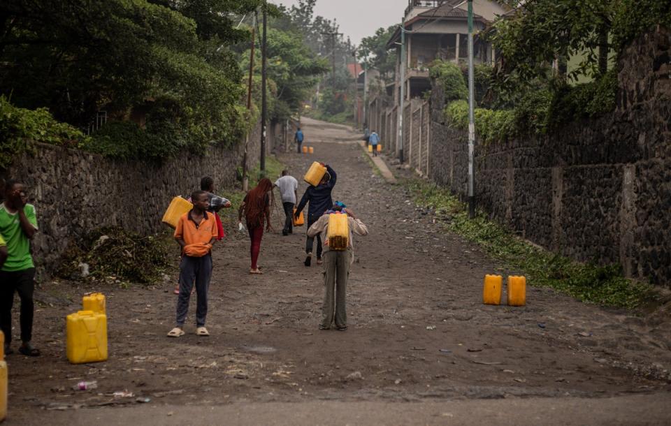 Residents leave their homes to fetch water from Lake Kivu as fighting subsides in Goma on Tuesday morning (AFP via Getty)