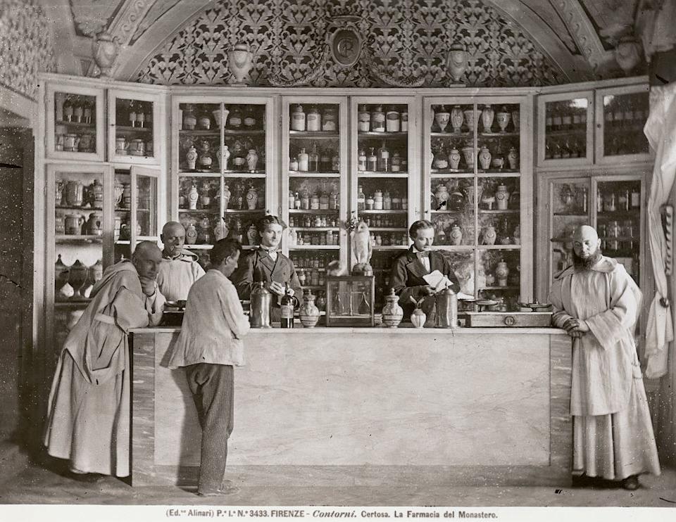 Historical photo of monks in an apothecary with jars on shelves, likely preparing herbal remedies in a monastery setting