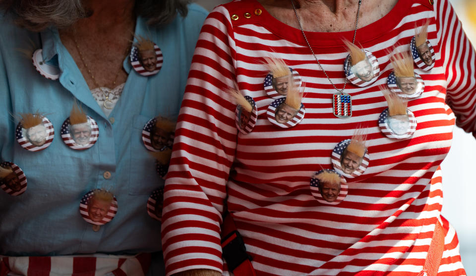 People wearing shirts with multiple buttons featuring an image of a Donald Trump's face with hair attached