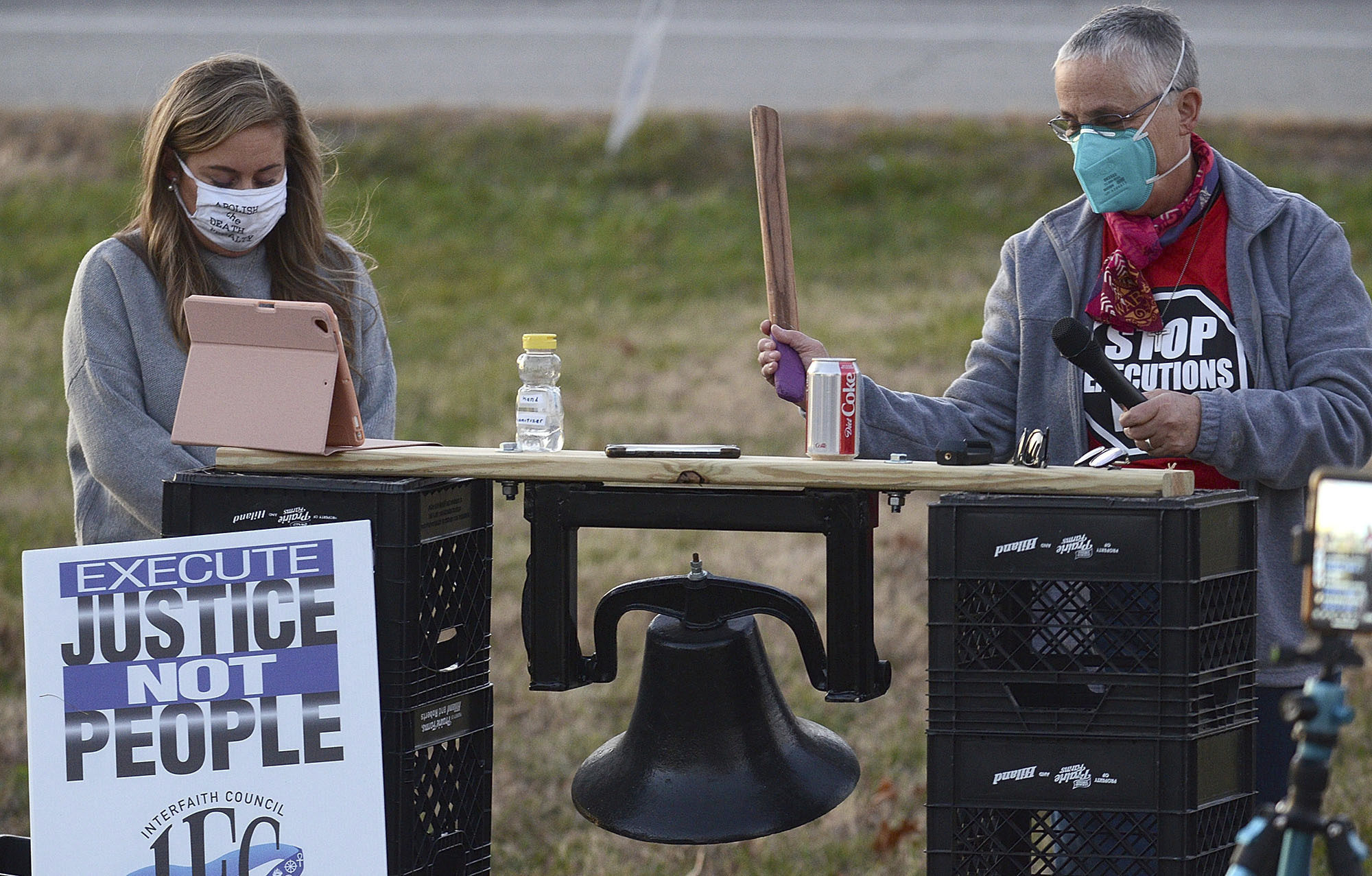 Sister Barbara Battista, right, tolls a bell before a minute of silence during the protest of the execution of Orlando Hall on Thursday, Nov. 19, 2020 across the street from the Federal Correctional Complex in Terre Haute, Ind. At left is attorney Ashley Kincaid-Eve. A federal judge halted the scheduled execution Thursday of Orlando Hall, a man convicted of kidnapping and raping a 16-year-old Texas girl, bludgeoning her with a shovel and burying her alive. ( Joseph C. Garza/The Tribune-Star via AP)